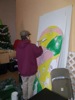 Patrick a AmeriCorps Volunteer painting a window mural for the Golden Rule